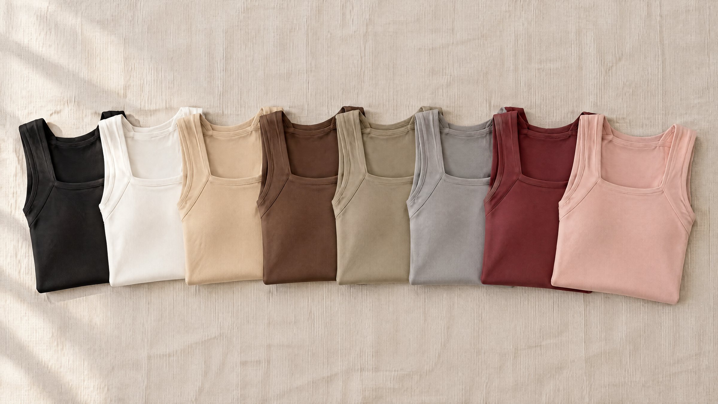 The eight colors of the Comfort Tank, folded and fanned out on linen